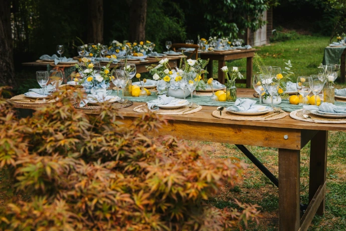 Outdoor tables set for a festive gathering with floral arrangements.
